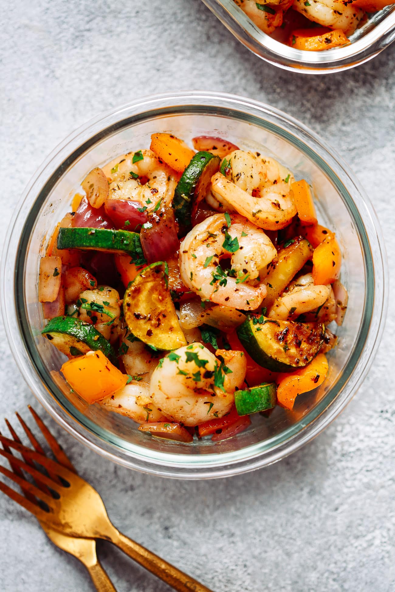 overhead view of a glass bowl containing garlic shrimp with lots of veggies 