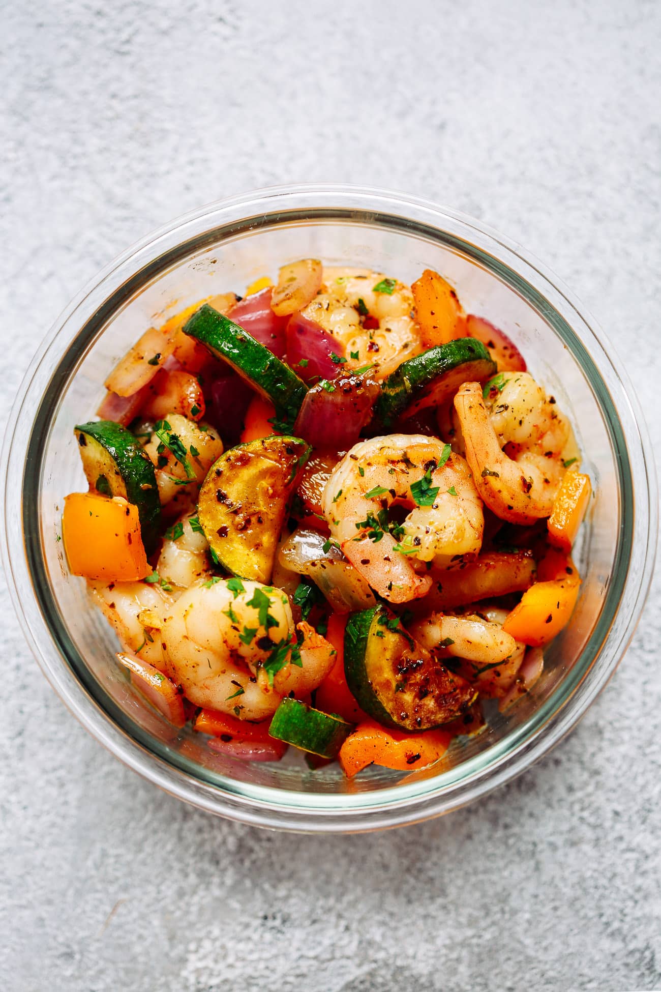 close up of a glass bowl containing lots of vegetables and cooked shrimp 