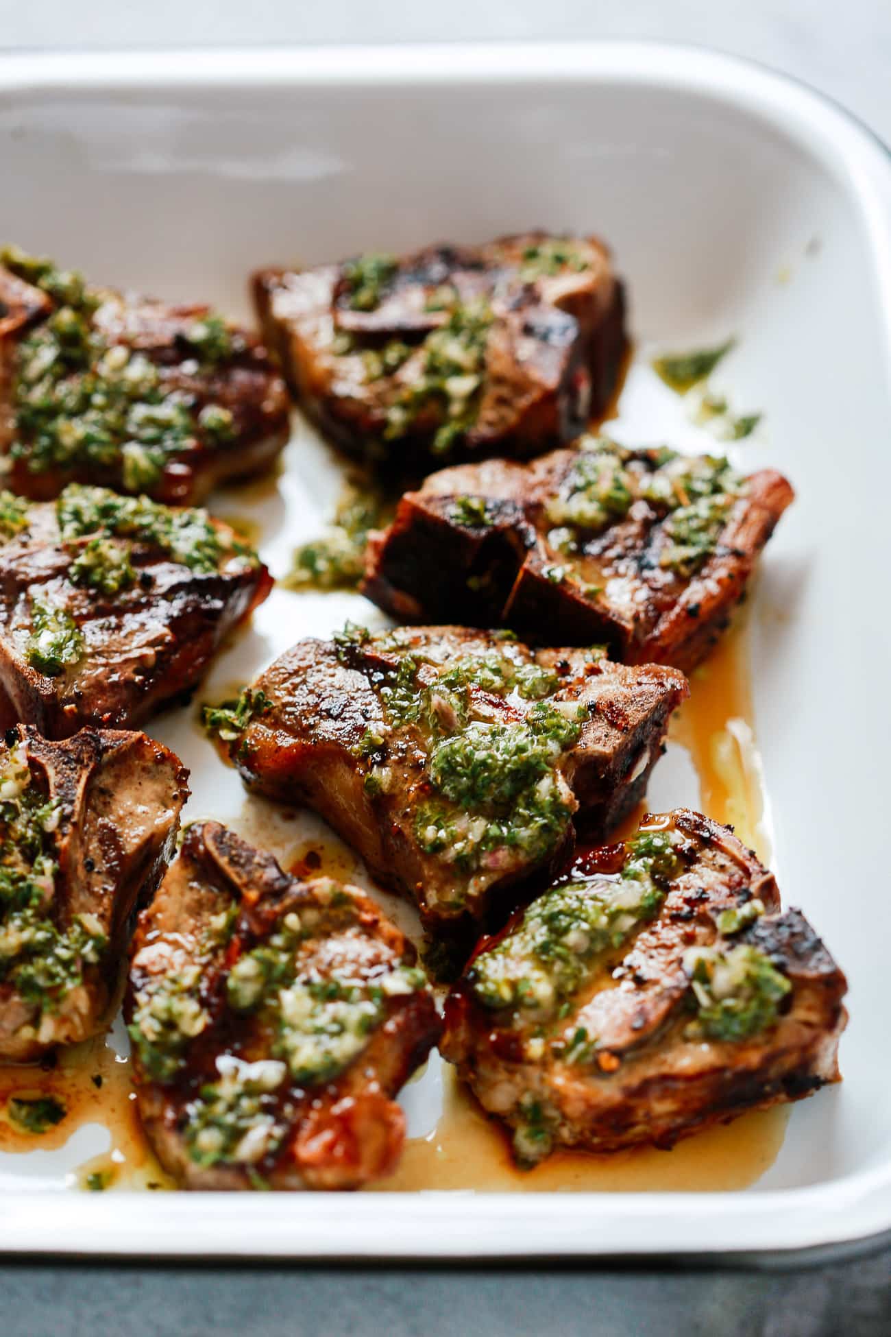 pan of lamb shoulder chops with fresh chimichurri sauce on top