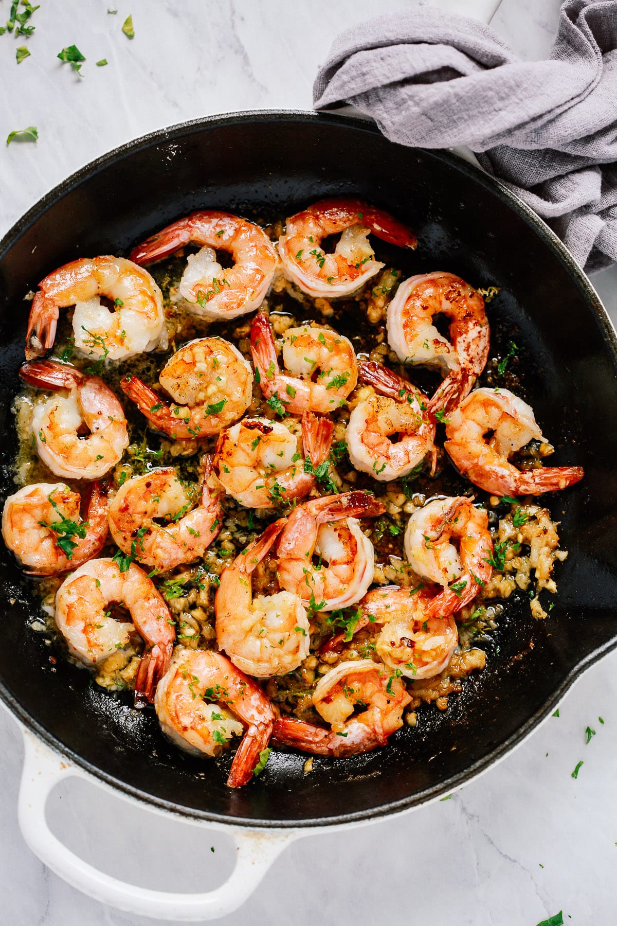 A white cast iron skillet with garlic butter shrimp inside.