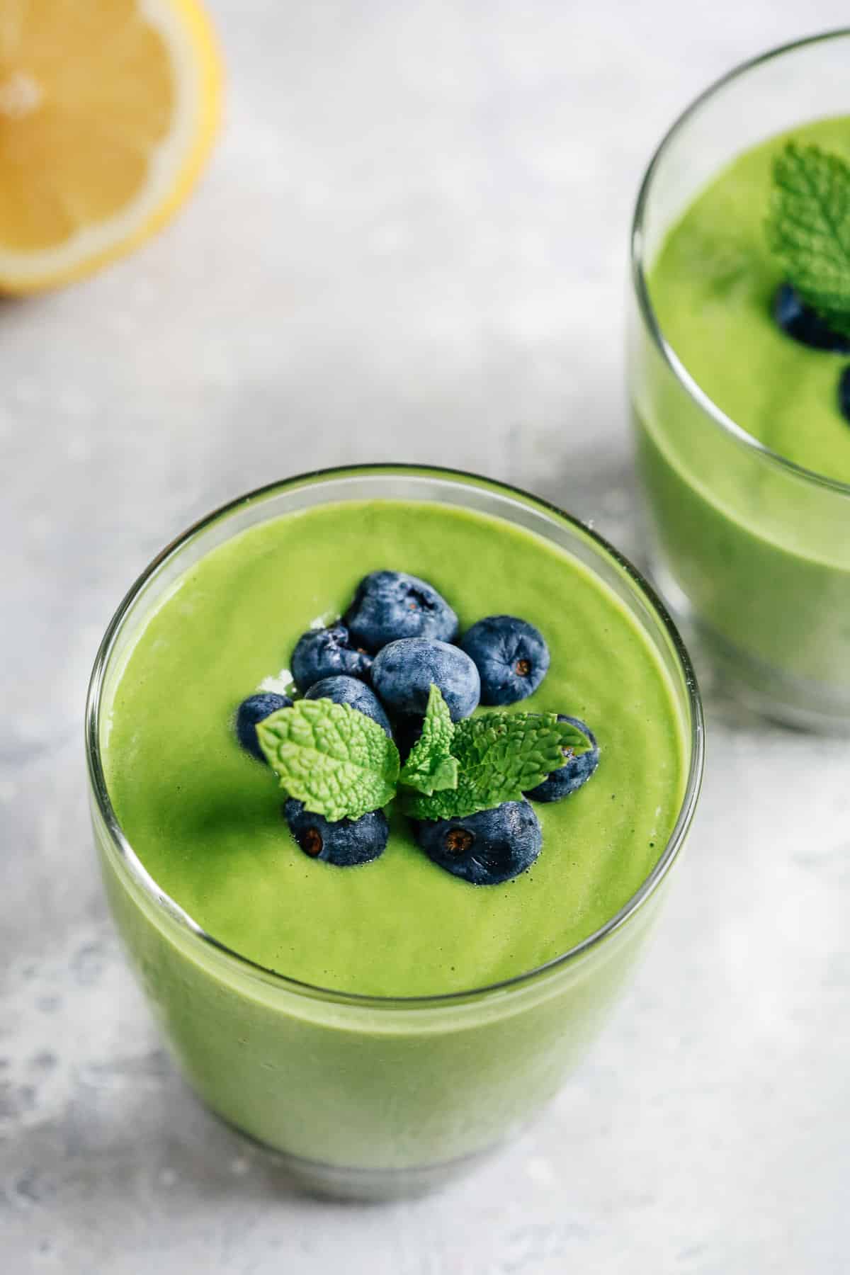 green protein shake topped with fresh blueberries and sprig of mint