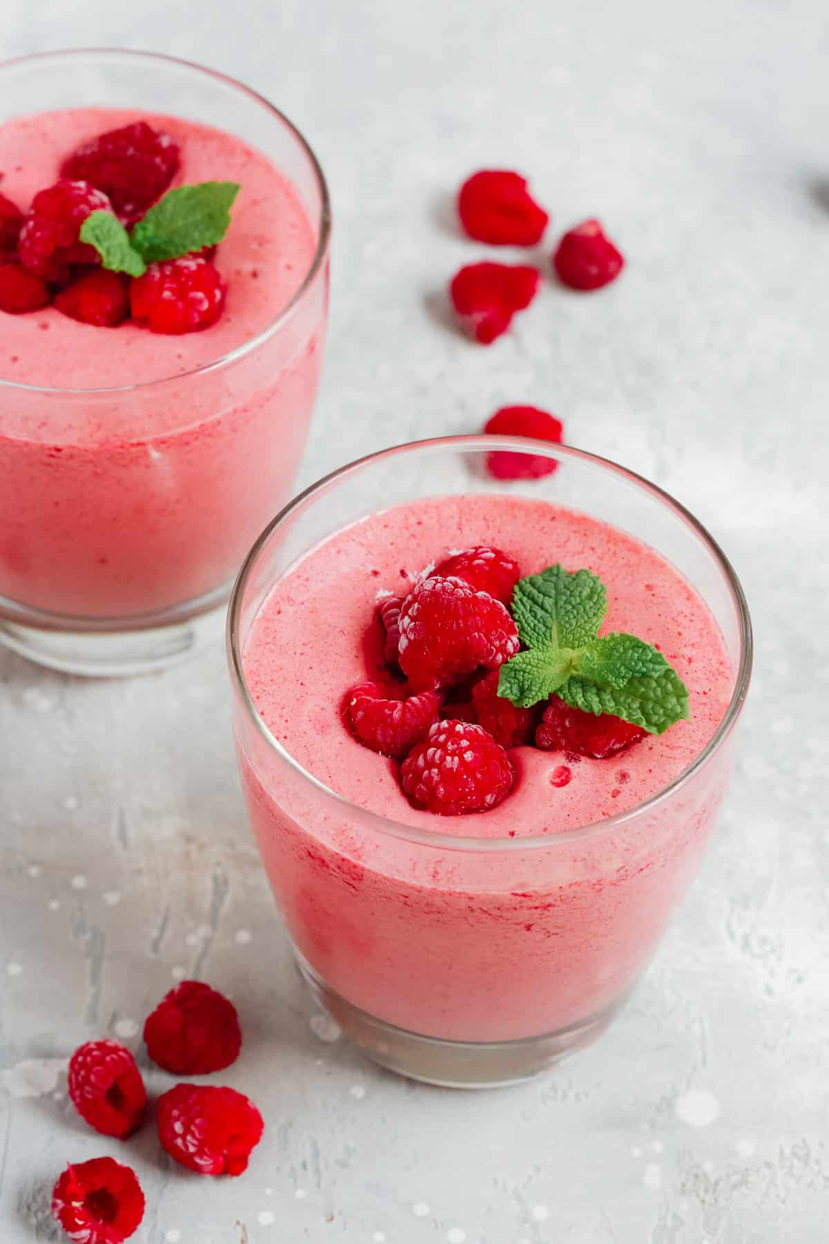This low carb raspberry smoothie will satisfy your sweet tooth while leaving you feeling full. It's low in carbs and packed with healthy fat and protein. low carb smoothie with raspberries in 2 drinking glasses