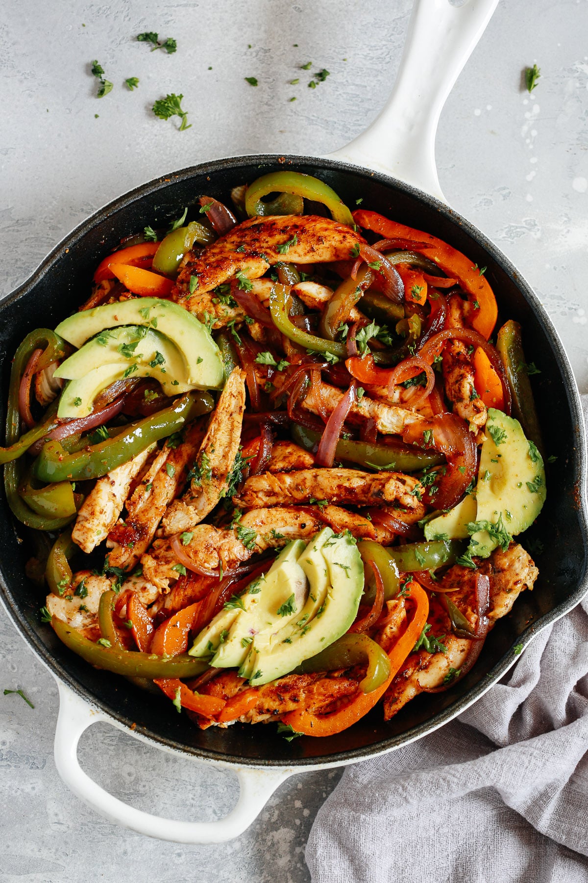 overhead view of a white skillet containing chicken fajitas inside.