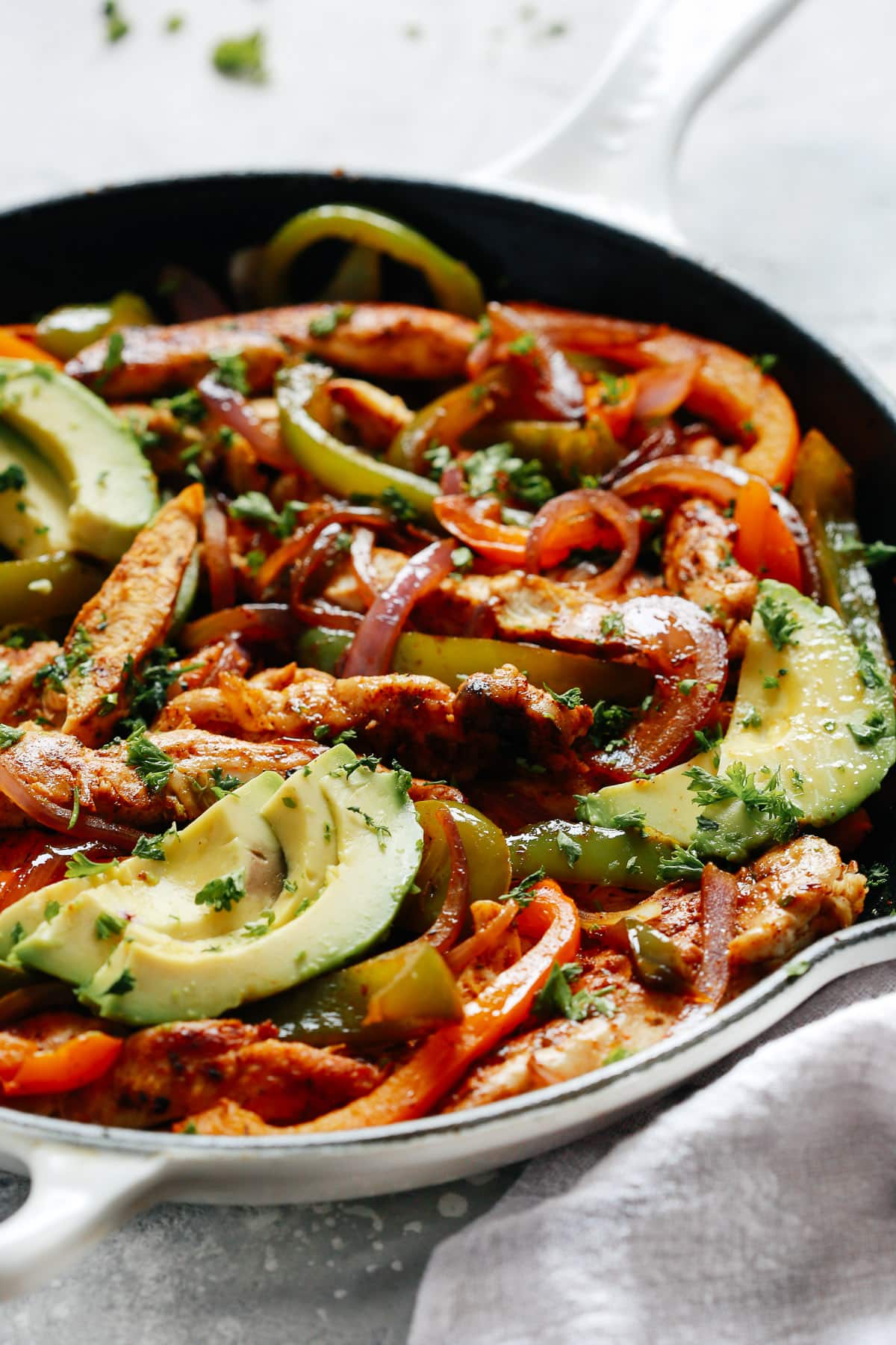 Skillet chicken fajitas are an easy weeknight one-pan meal. This Tex-Mex recipe has healthy protein and fresh veggies all in one amazing yet simple dish. Chicken Fajitas with avocado slices
