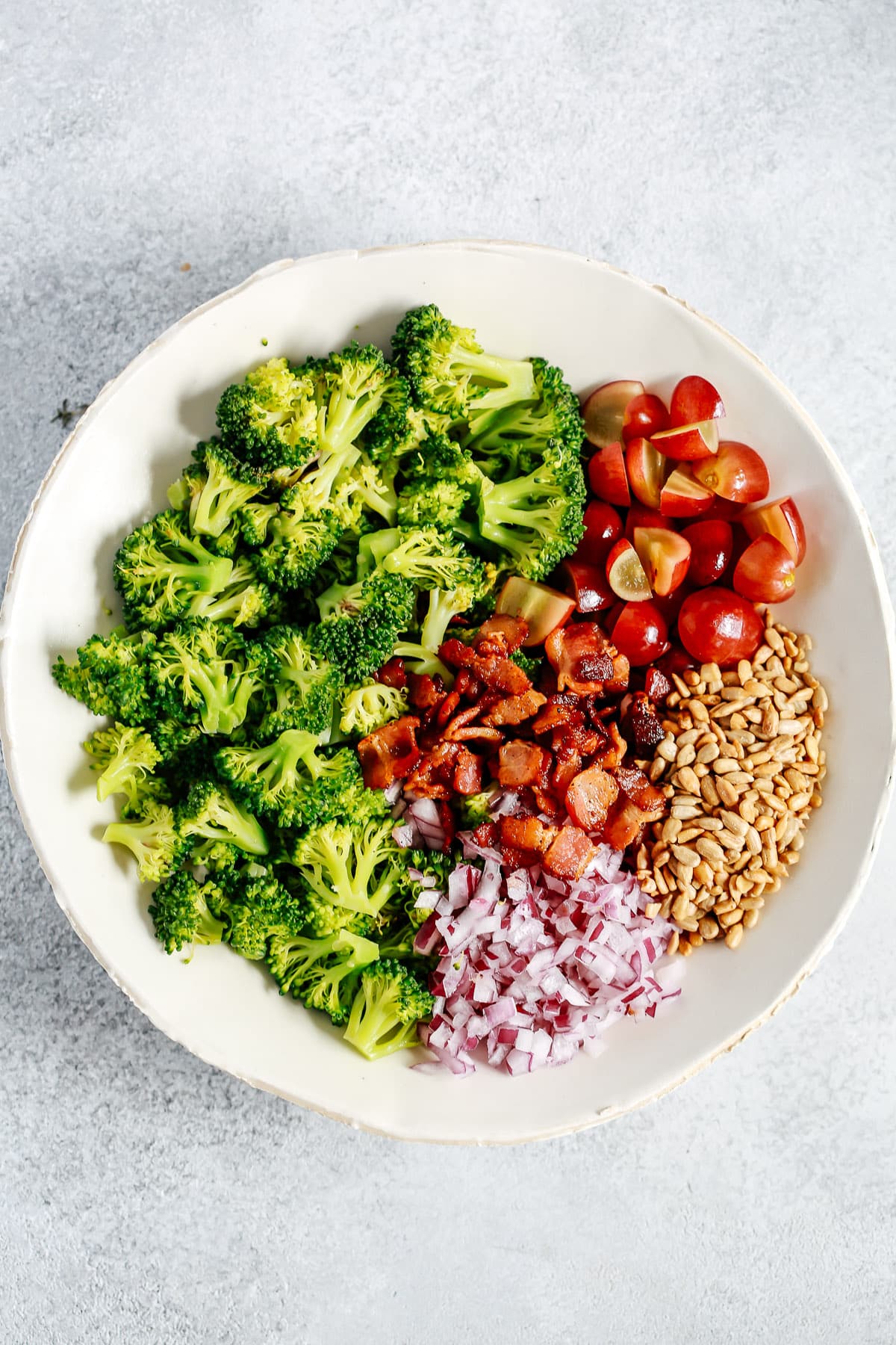 This simple broccoli salad will give you a colorful and nutritious dish in just 15 minutes. It makes a filling lunch or an impressive dinner side dish. salad in bowl with ingredients separated into clusters