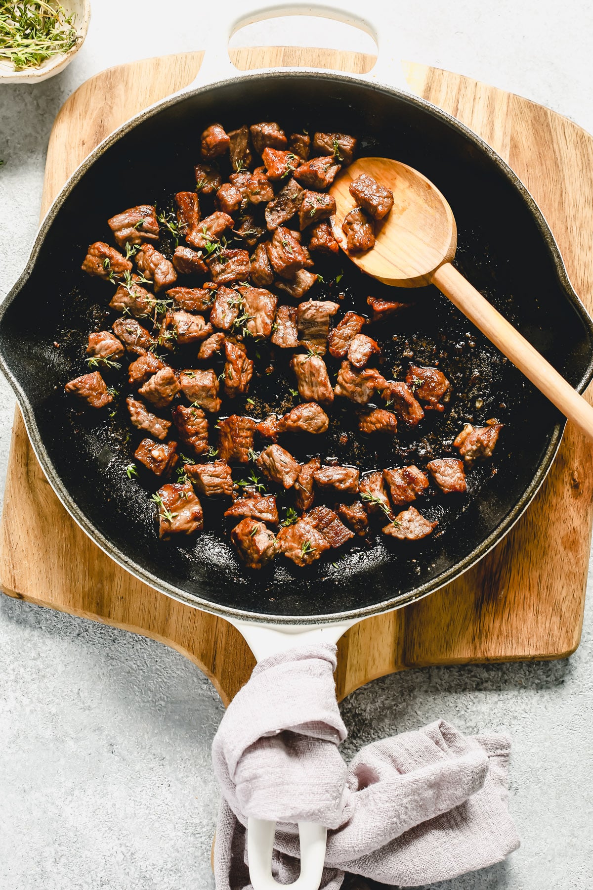 overhead view of a white skillet containing steak bites inside.