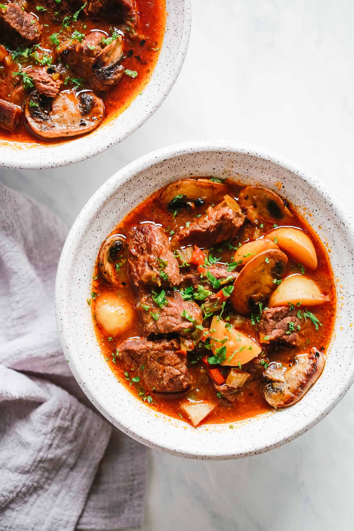 overhead view of two white bowls containing beef stew