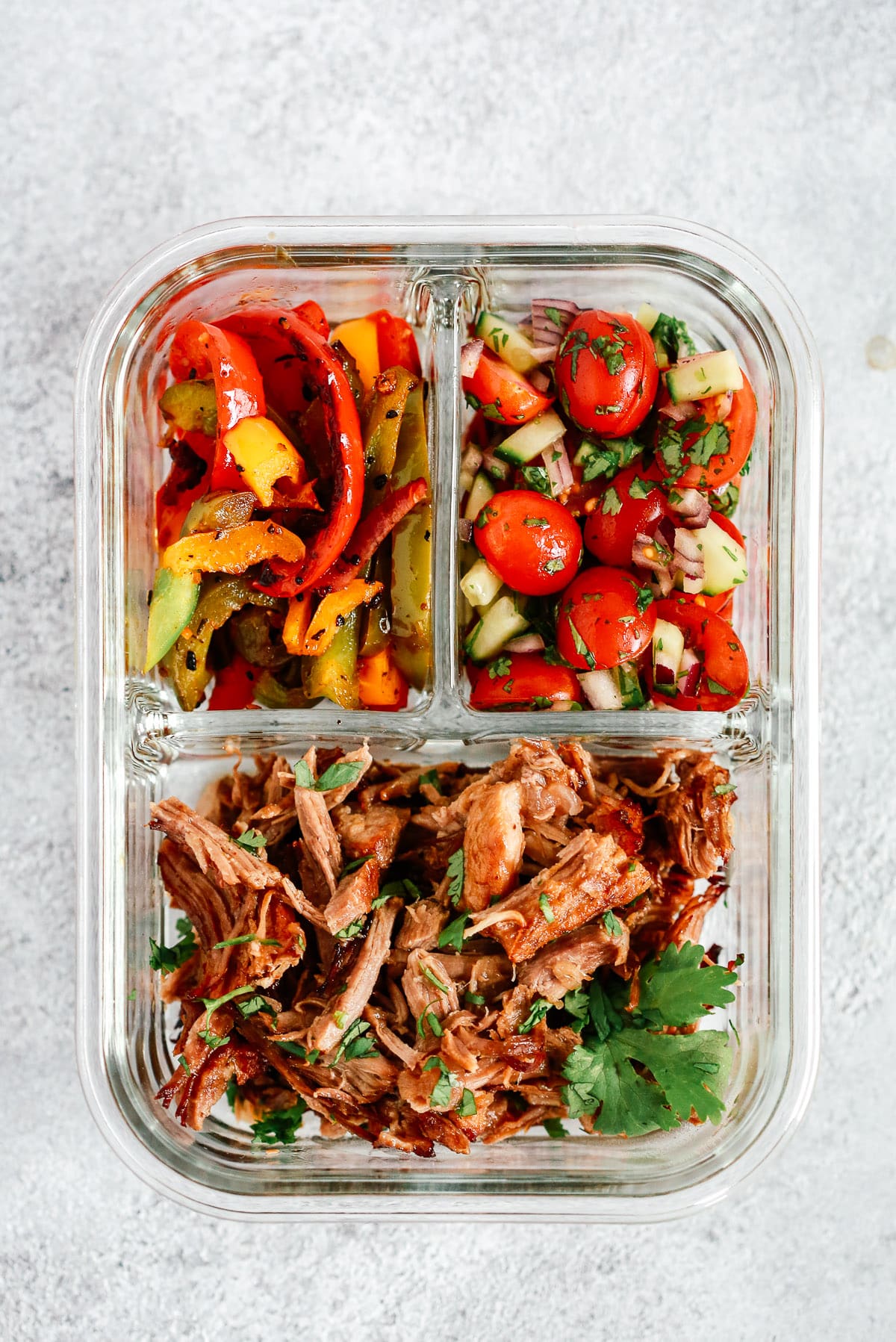 meal prep container with Mexican pulled pork, sauteed peppers and tomato salsa