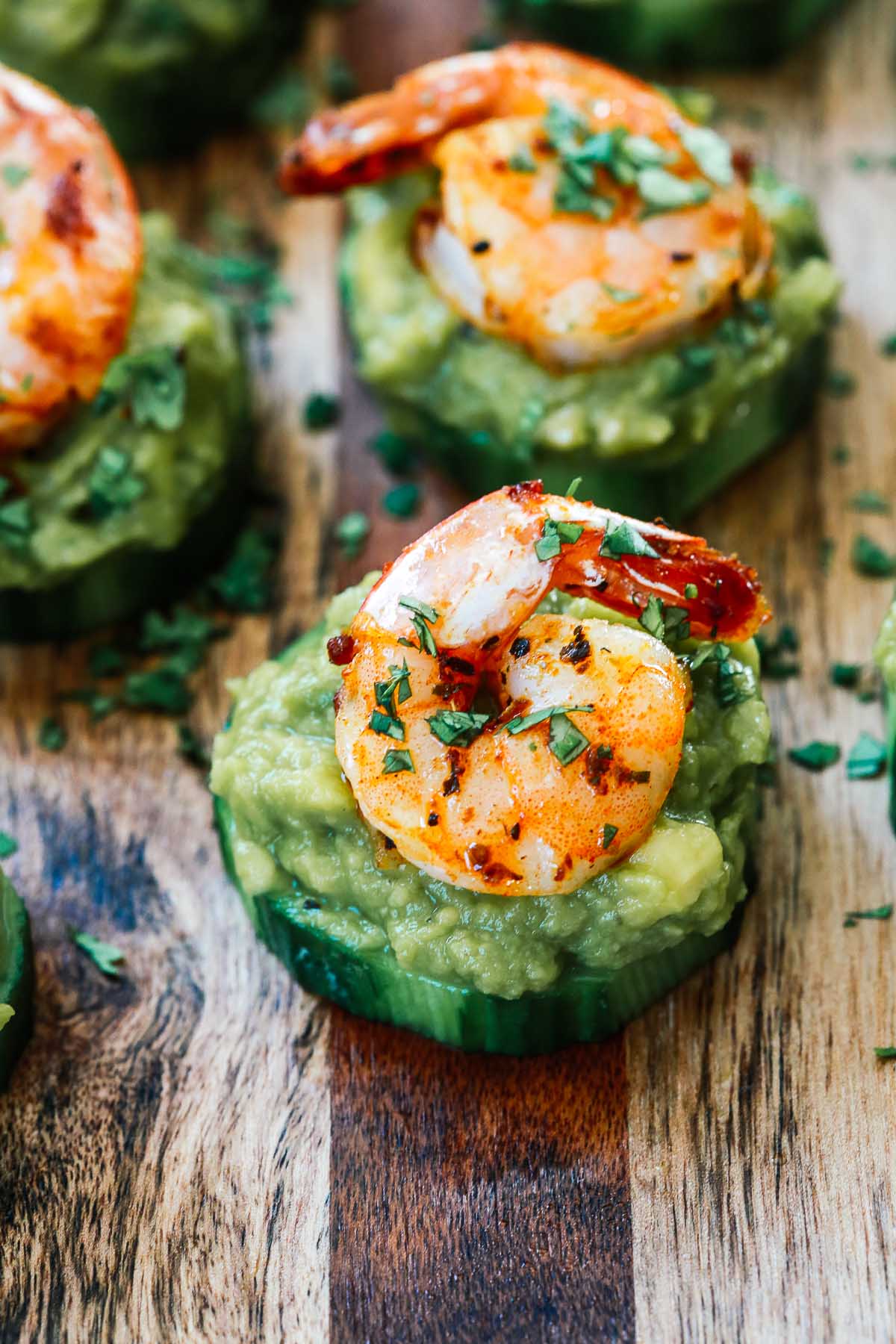 Slices of cucumber topped with guacamole and shrimp