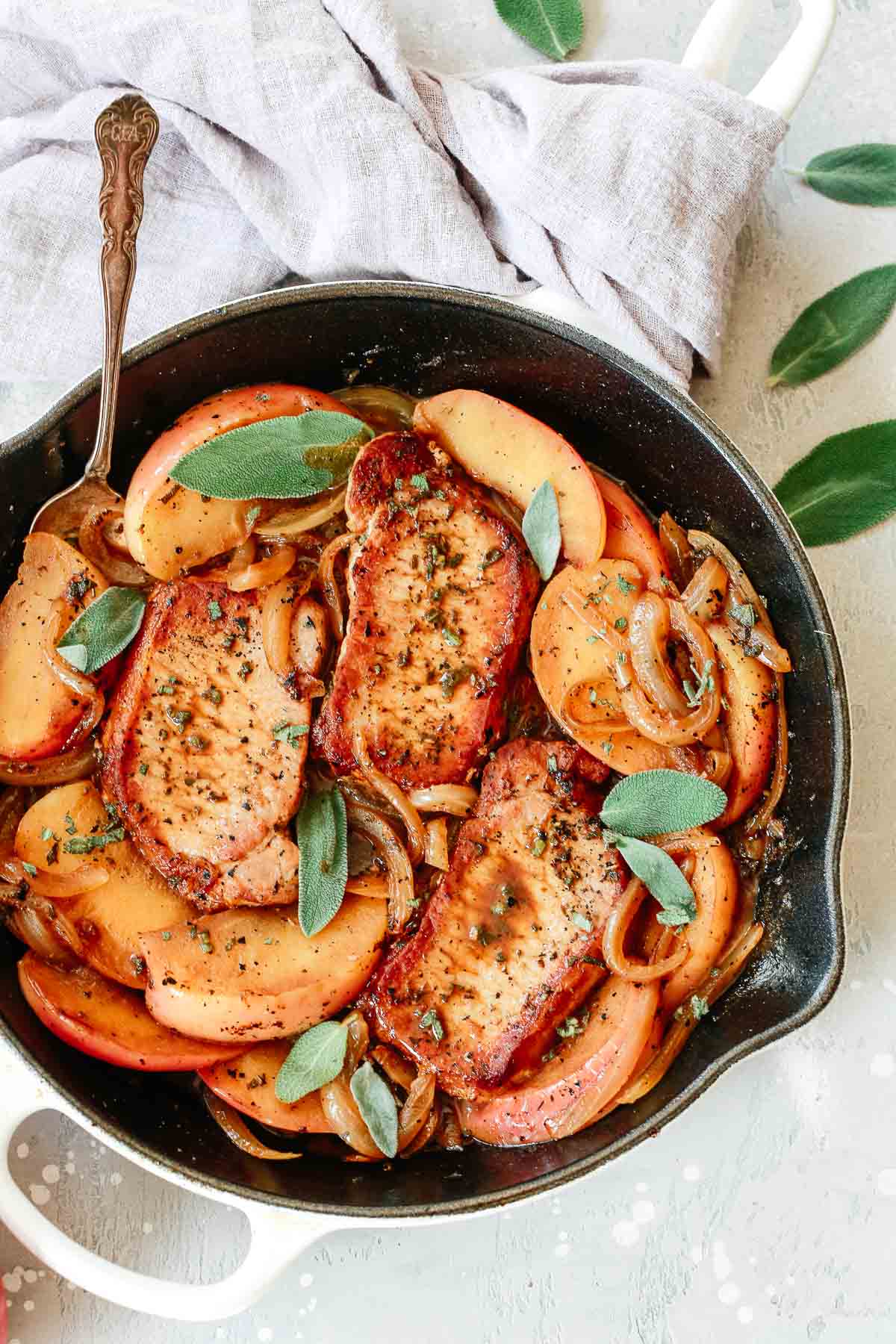 close up of a cast iron skillet containing  Onion, apple and Pork Chop