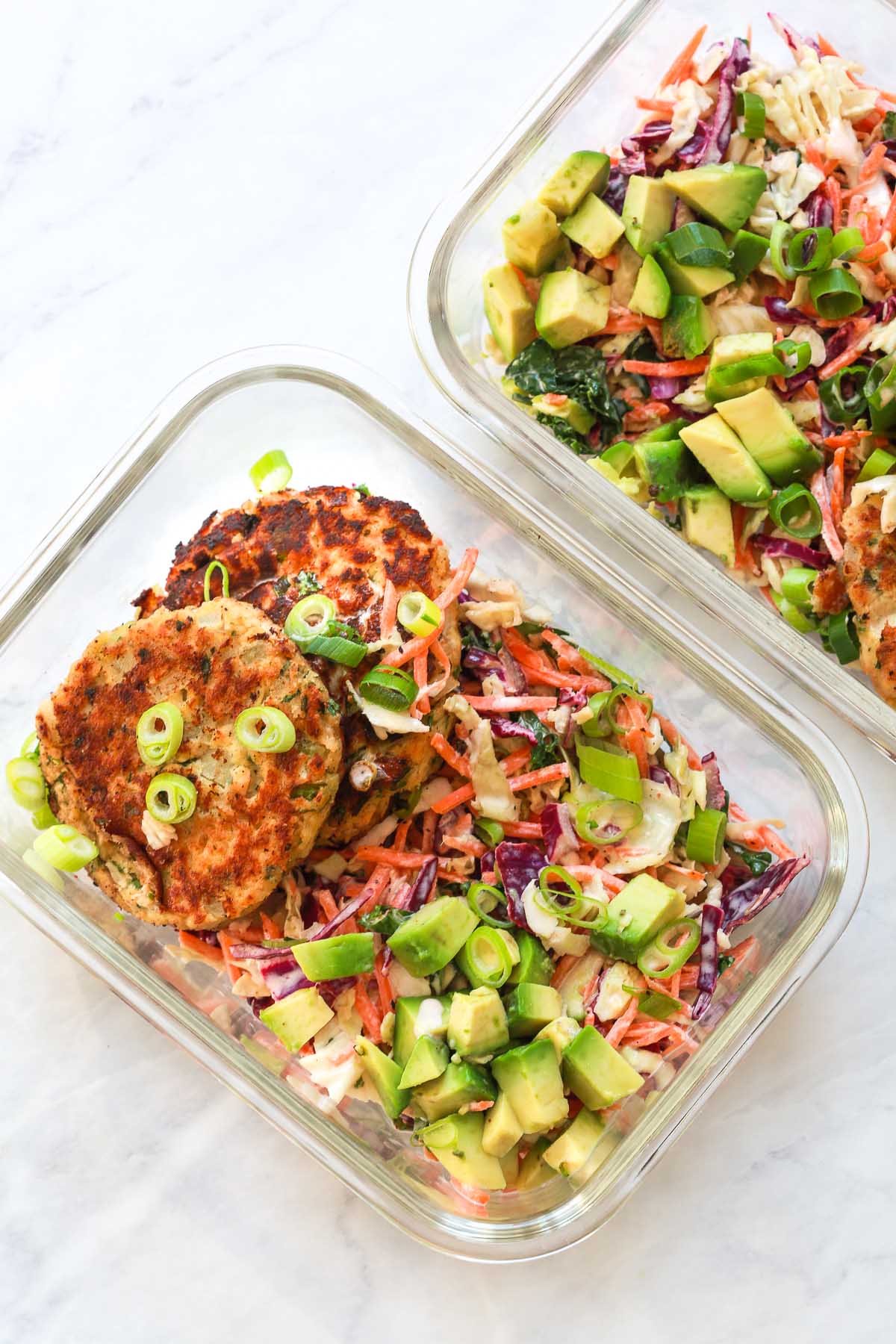 Two meal prep containers of salmon patties with coleslaw.