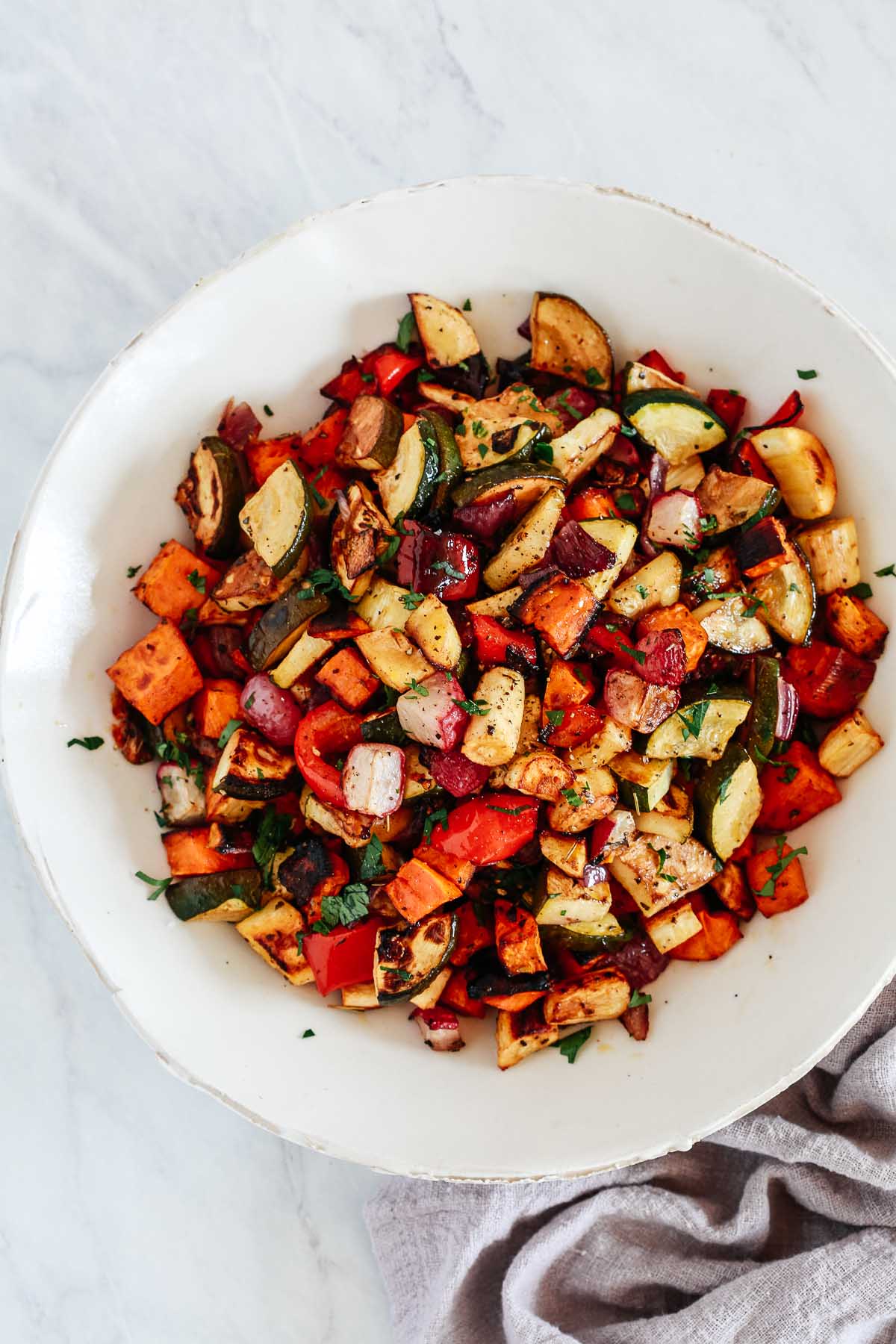 An overhead photo of a white bowl with balsamic roasted veggies inside.