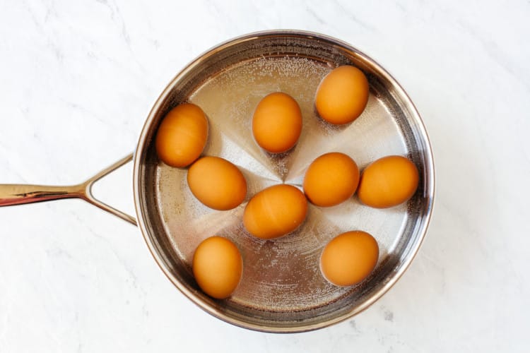 a pan filled with water and 9 eggs to be boiled.