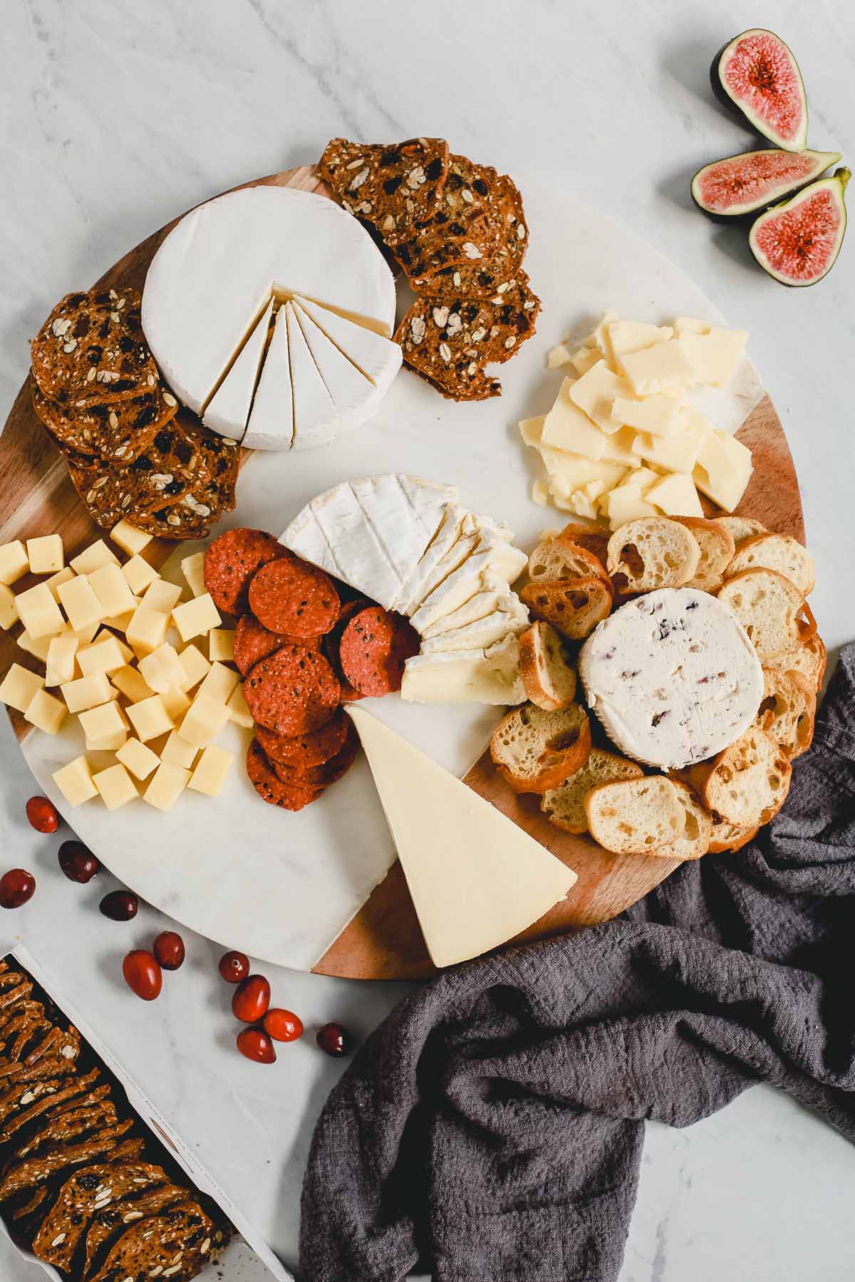 arranging a charcuterie board with meat, cheese, crackers, and fruit