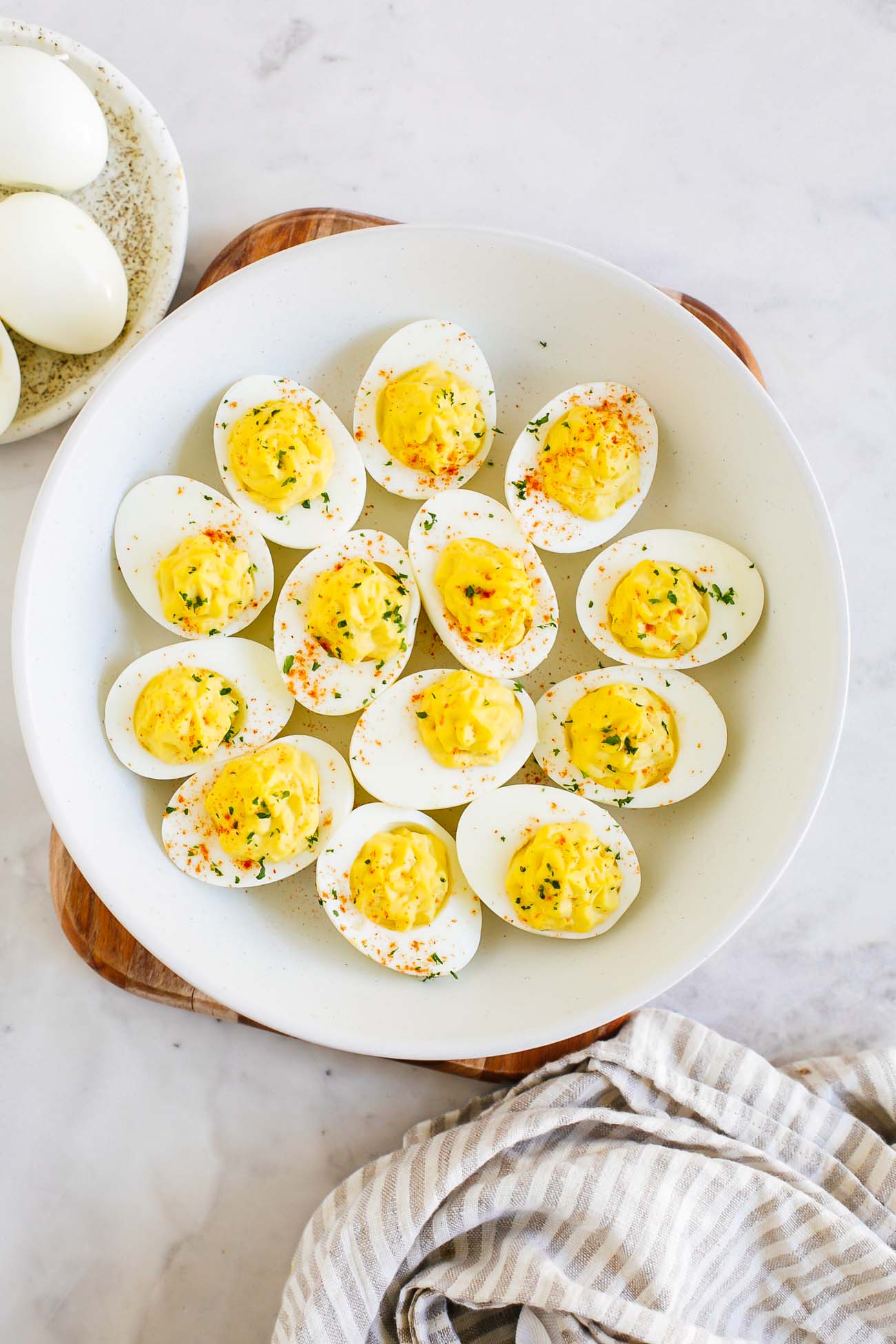A platter of easy deviled eggs garnished with chives and paprika.