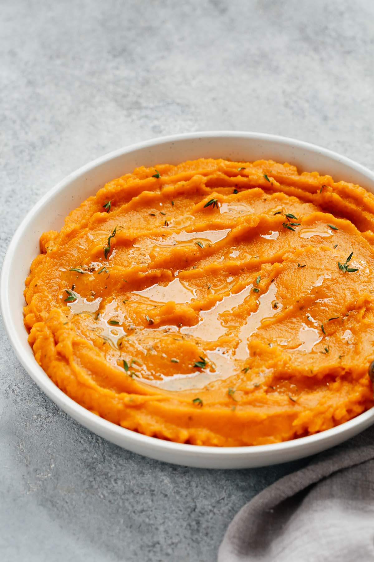Savory mashed sweet potatoes are a great alternative to the sweet yams or starchy white potatoes often found on the holiday table. This healthy side dish recipe is sure to be requested for every holiday meal. Closeup view of a bowl of Healthy Mashed Sweet Potatoes