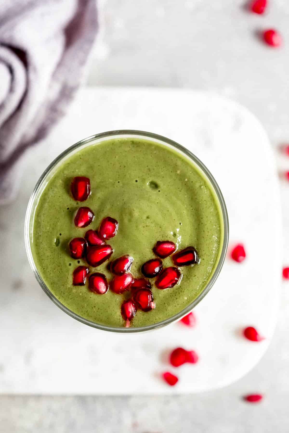 overhead view of a green smoothie in a tall glass with a straw 