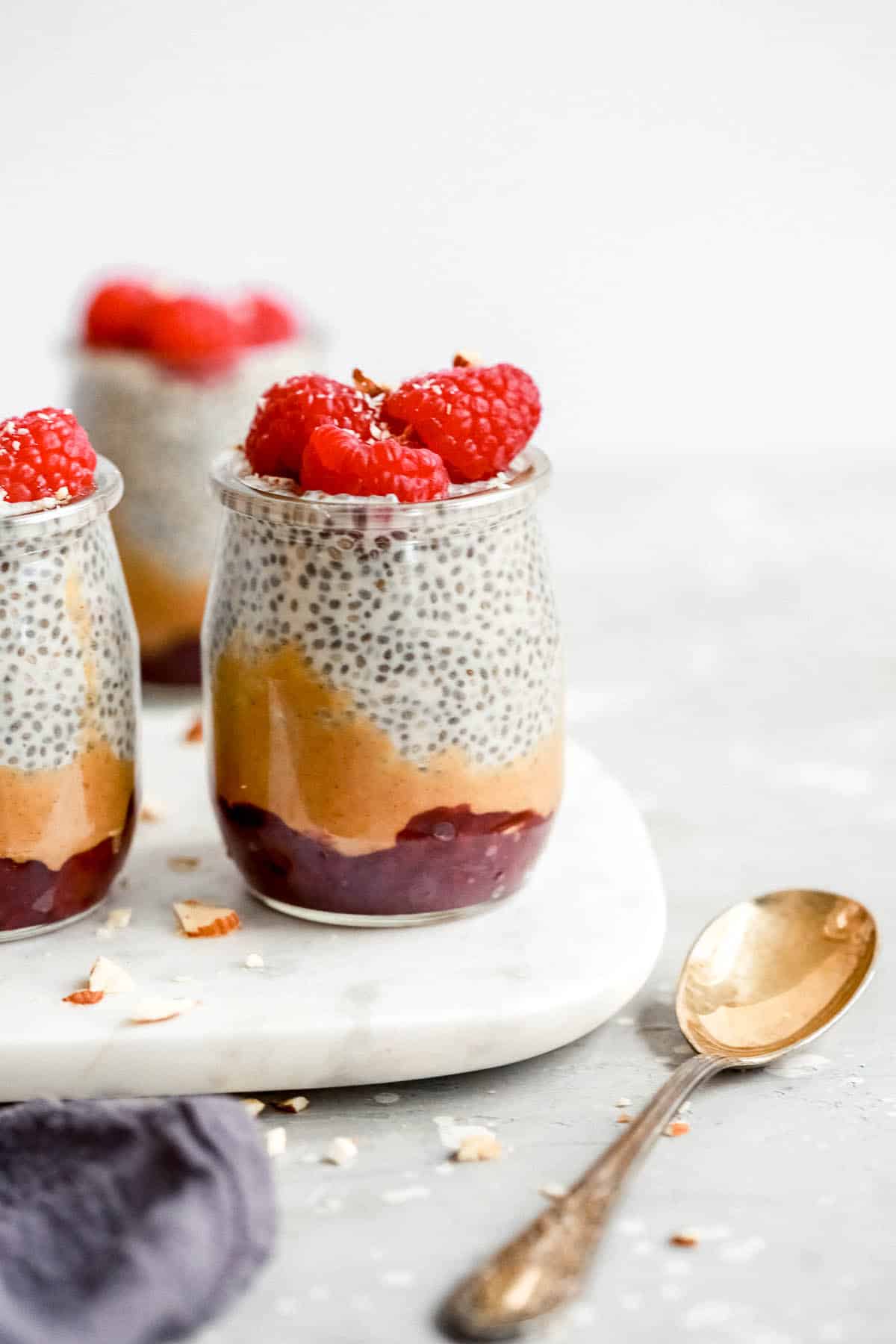 chia seed pudding topped with raspberries in small glass jars