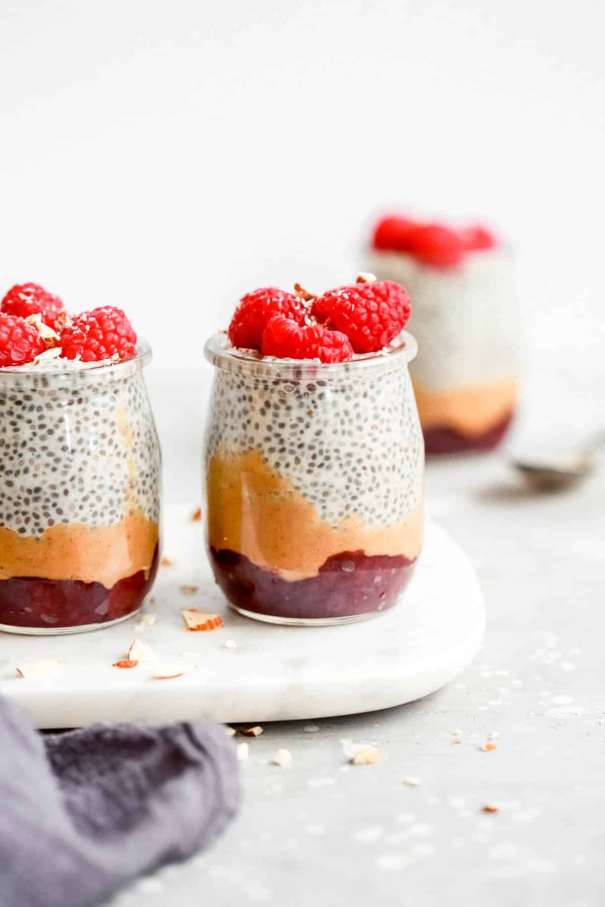 chia seed pudding topped with raspberries in small glass jars