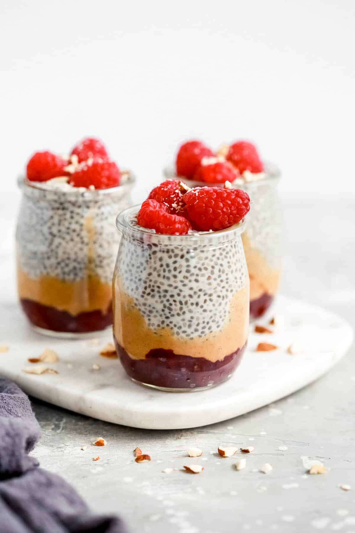 chia seed pudding topped with raspberries in small glass jars