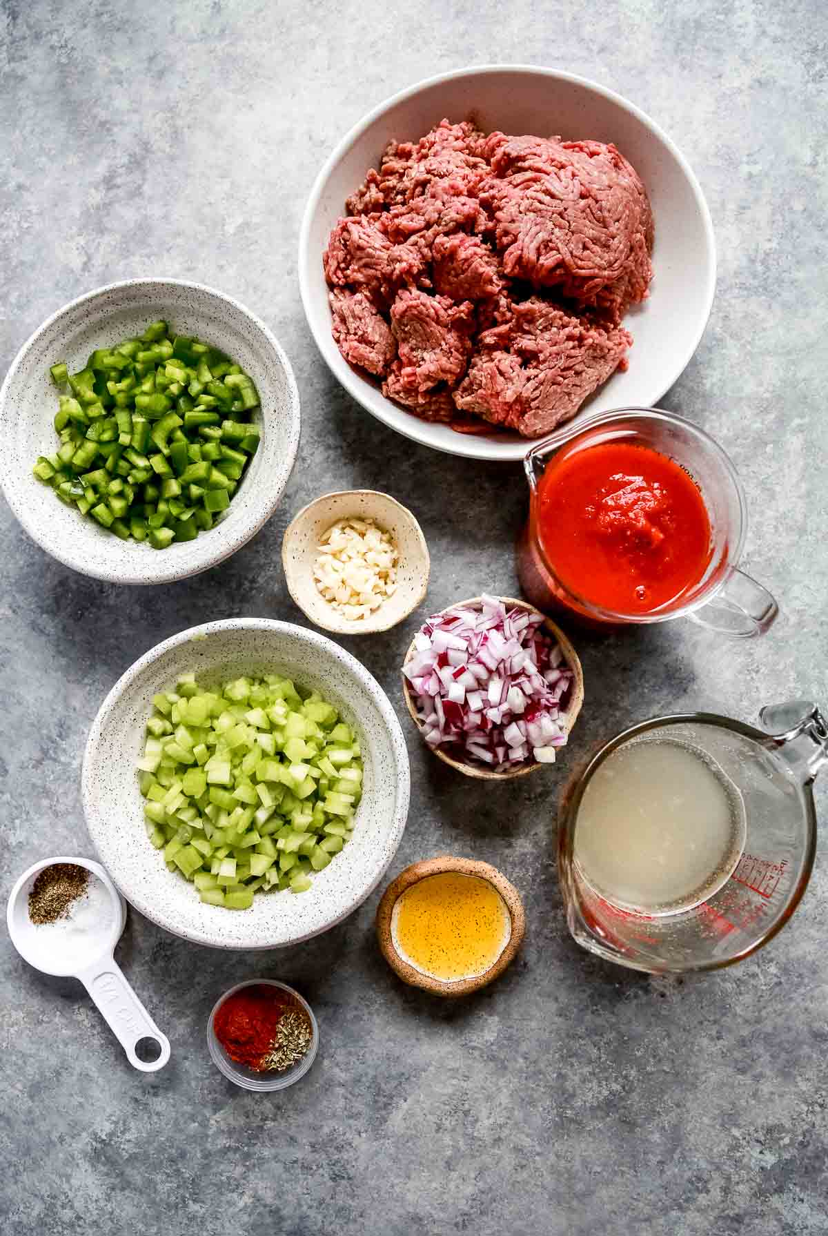 bowls and measuring cups holding all the ingredients for keto chili such as ground beef, peppers and onions