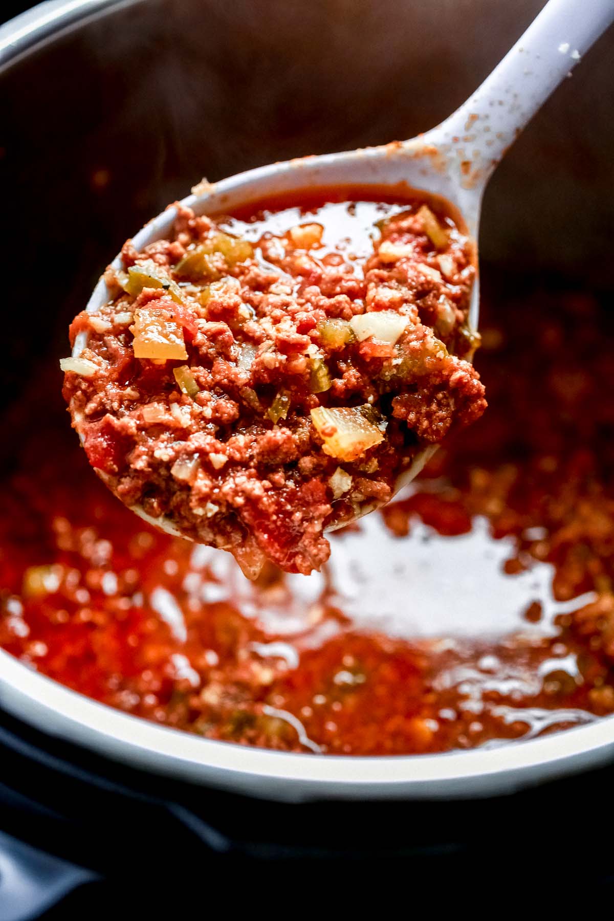 close up of chili on a spoon held over a pot