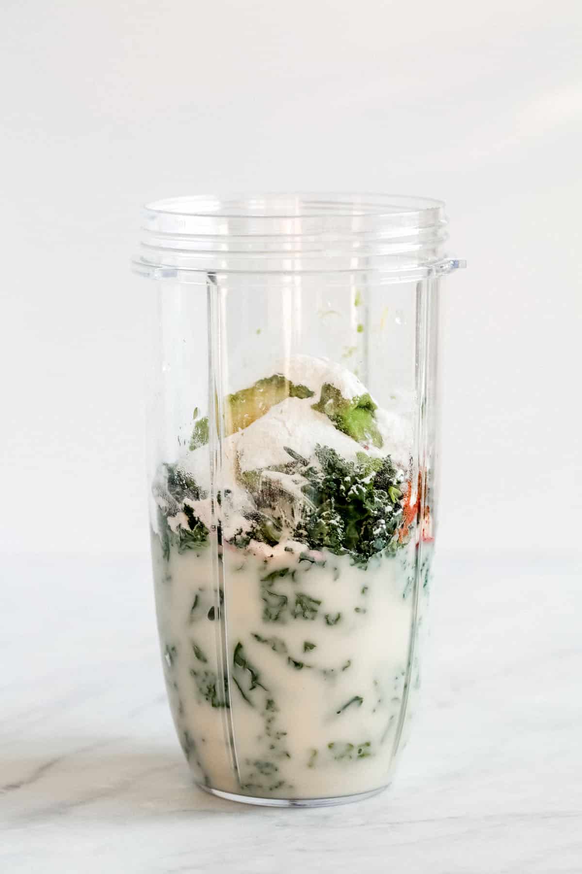 milk, kale and avocado in a blender cup
