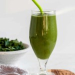 green keto smoothie in a tall glass with a straw