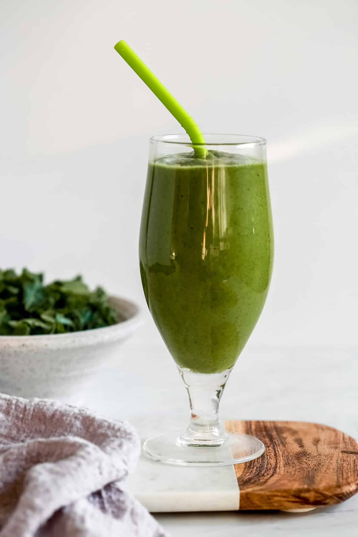 green keto smoothie in a tall glass with a straw 