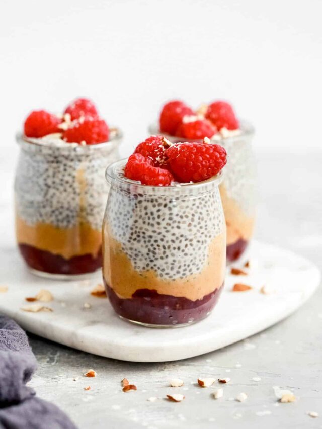 chia seed pudding topped with raspberries in small glass jars