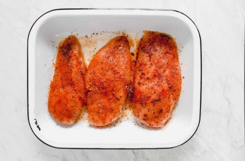 seasoned raw chicken breast in a baking pan