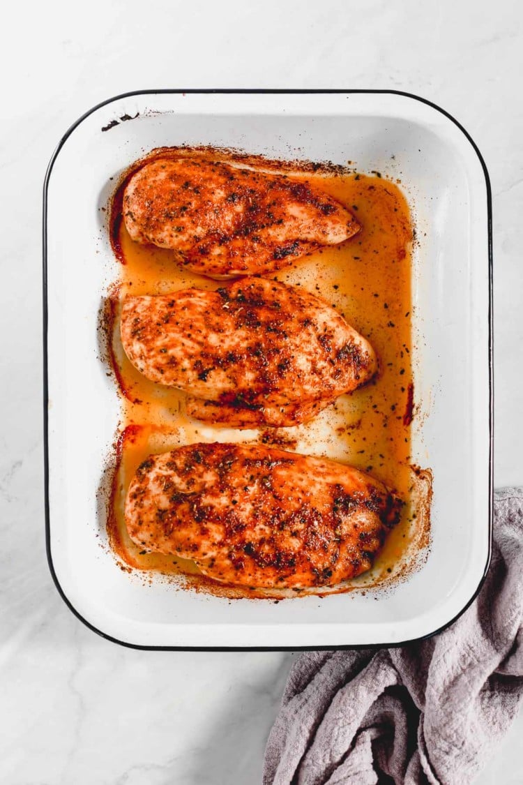 overhead view of baked chicken breast in a baking pan