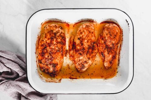 overhead view of baked chicken breast in a baking pan