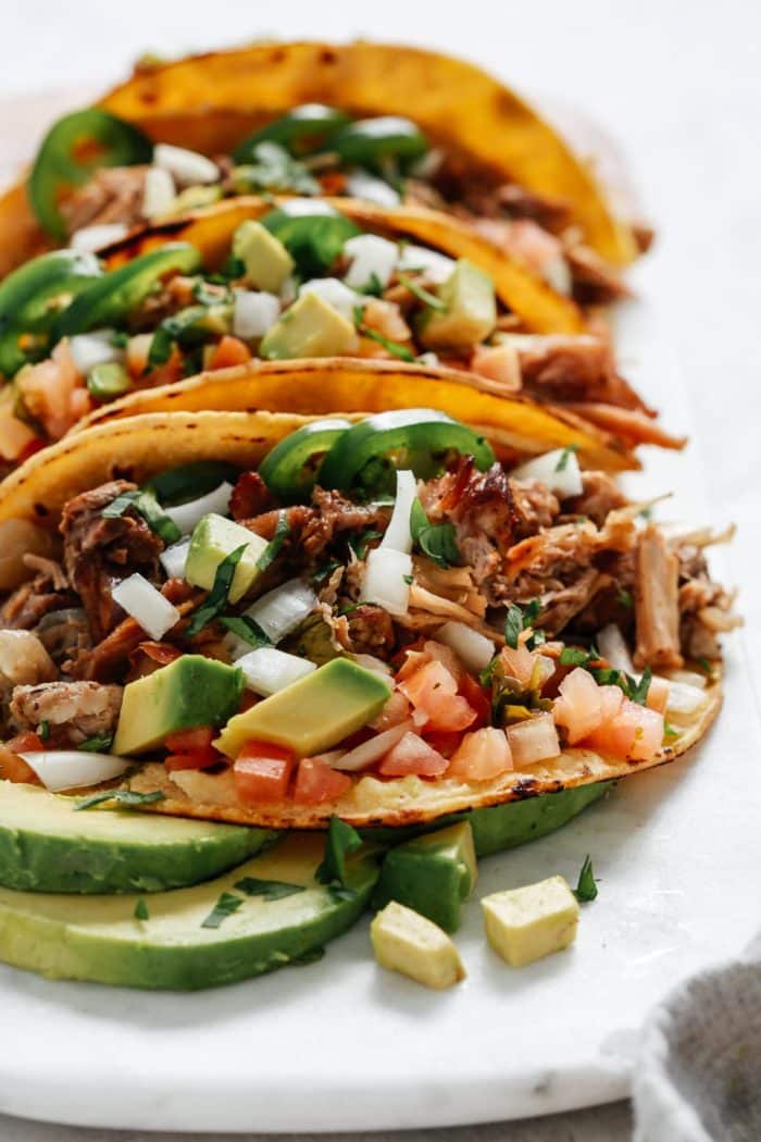 close up image of shredded Mexican pork with fresh avocado in taco shells