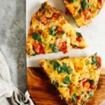 vegetable frittata cut into pieces on a wooden serving board