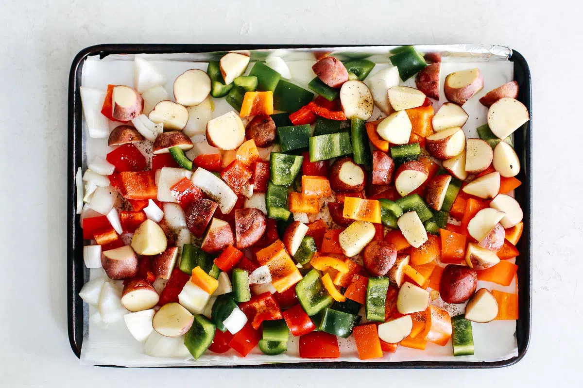 chopped colorful bell peppers, potatoes, and onions on a baking sheet, ready for roasting