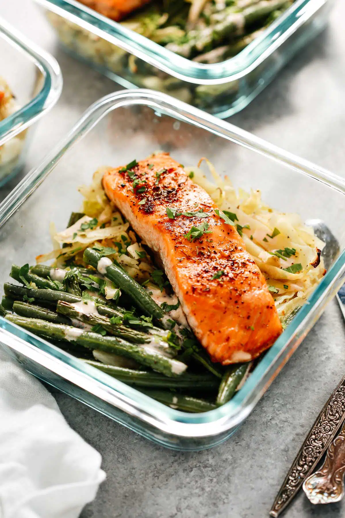 broiled salmon filet in meal prep container with green beans and cabbage