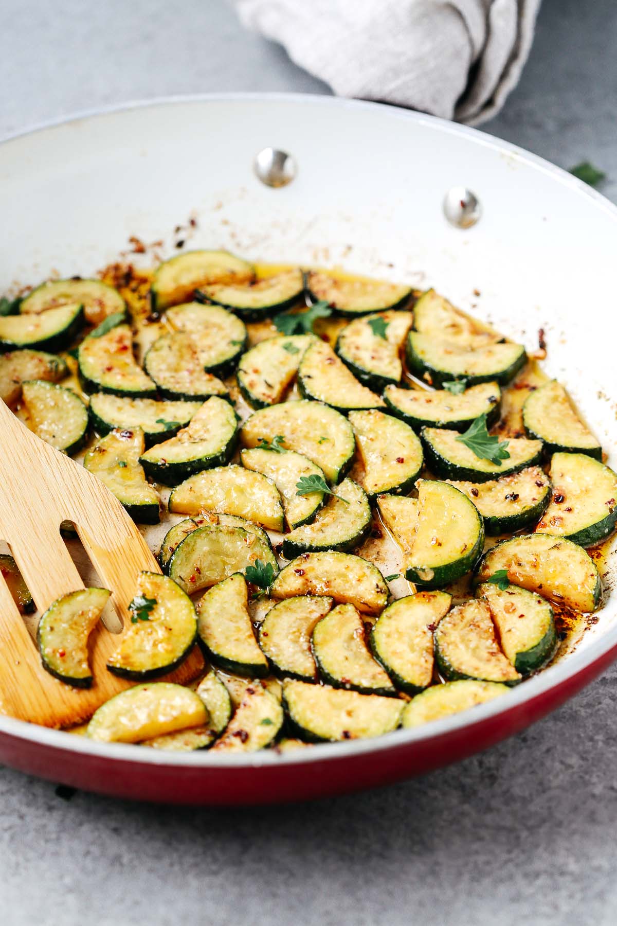 zucchini cooking in a white skillet.