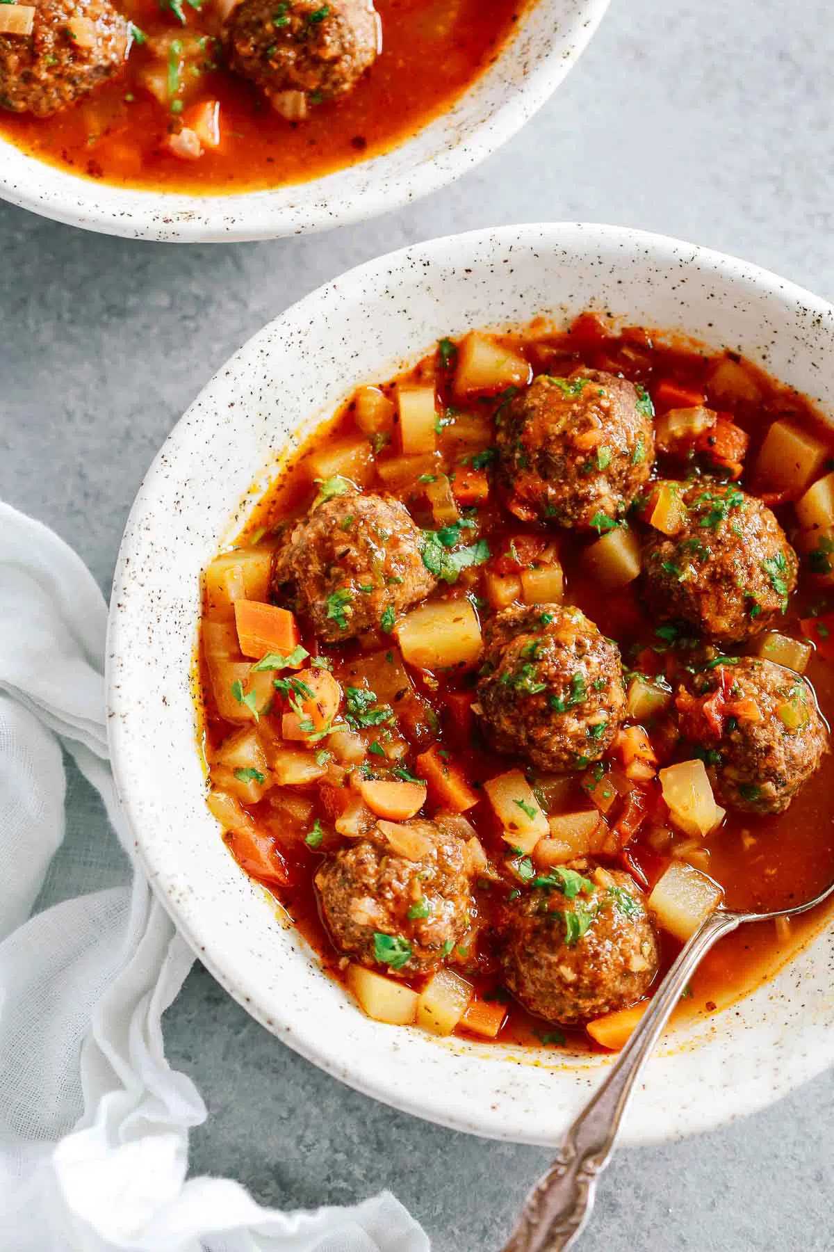 overhead view of meatball soup in a white bowl