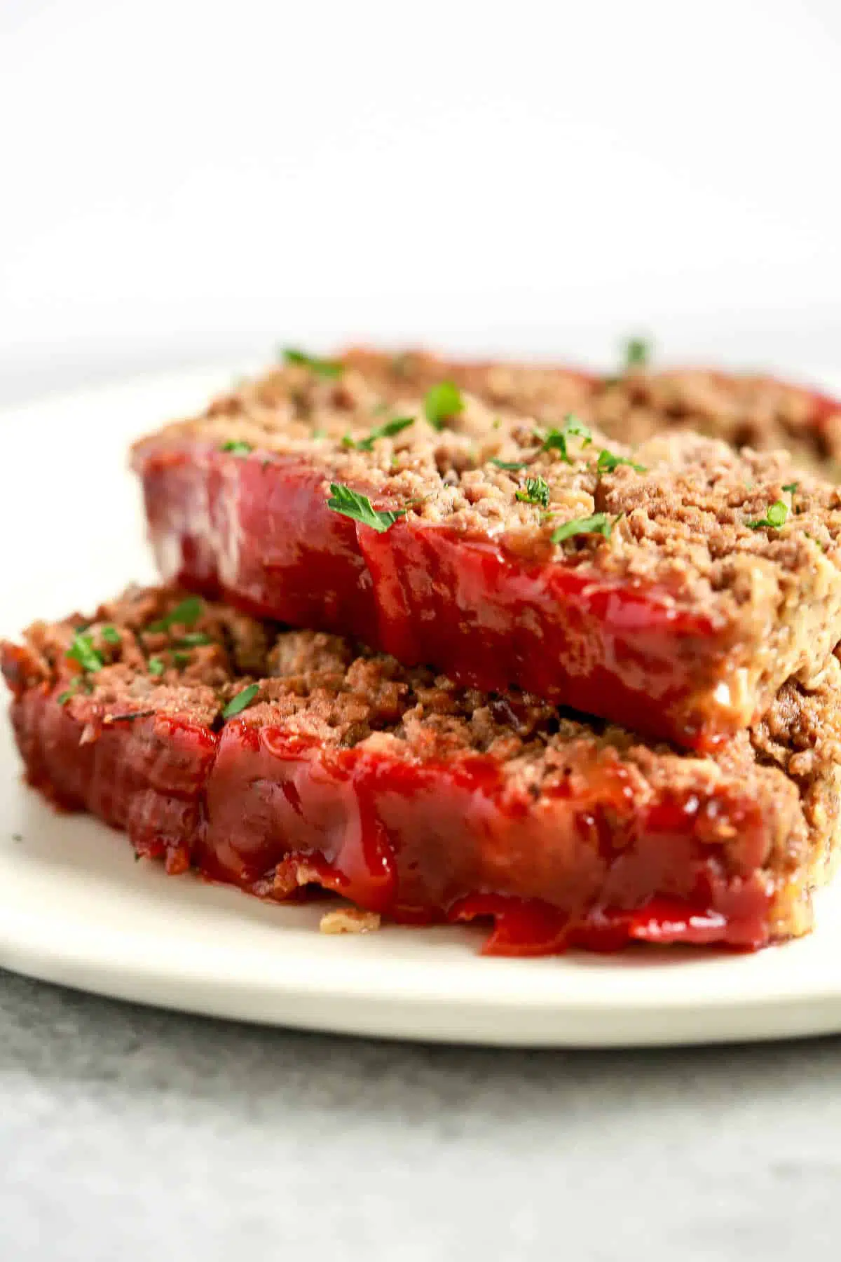 close up image: two slices of healthy meatloaf with tomato sauce on top