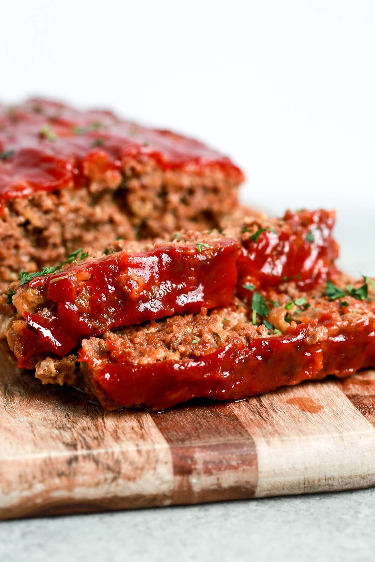 slices of homemade meatloaf with tomato sauce on top on cutting board