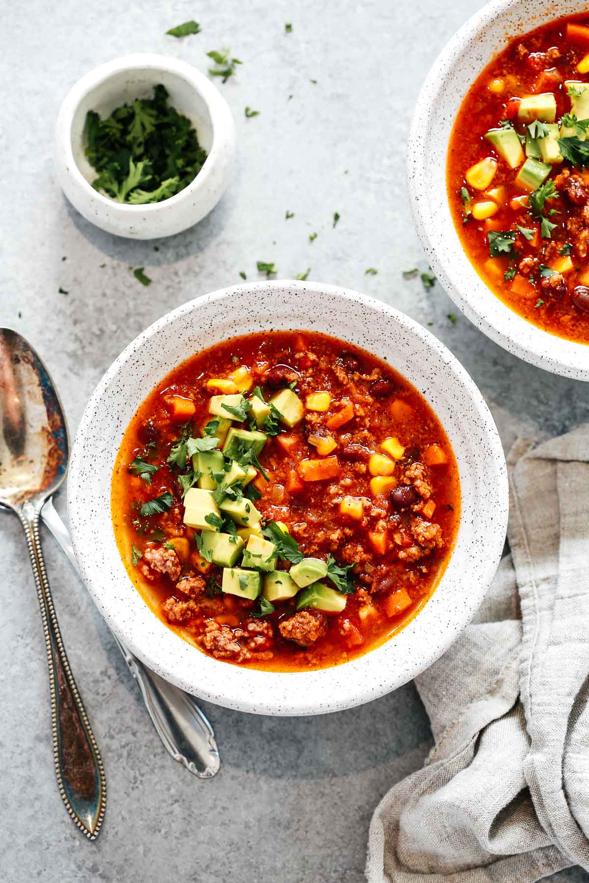 Instant Pot taco soup in a white bowl with avocado on top.