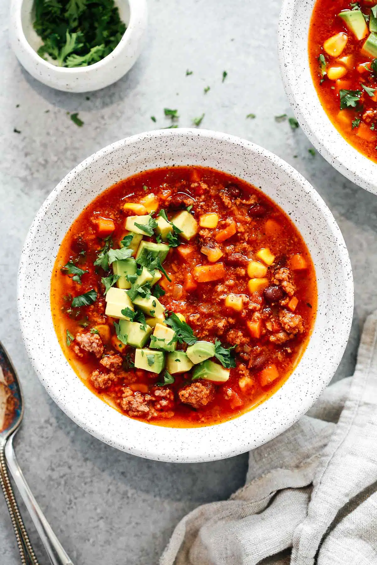 overhead view of a bowl of Mexican taco soup with chopped avocado garnish