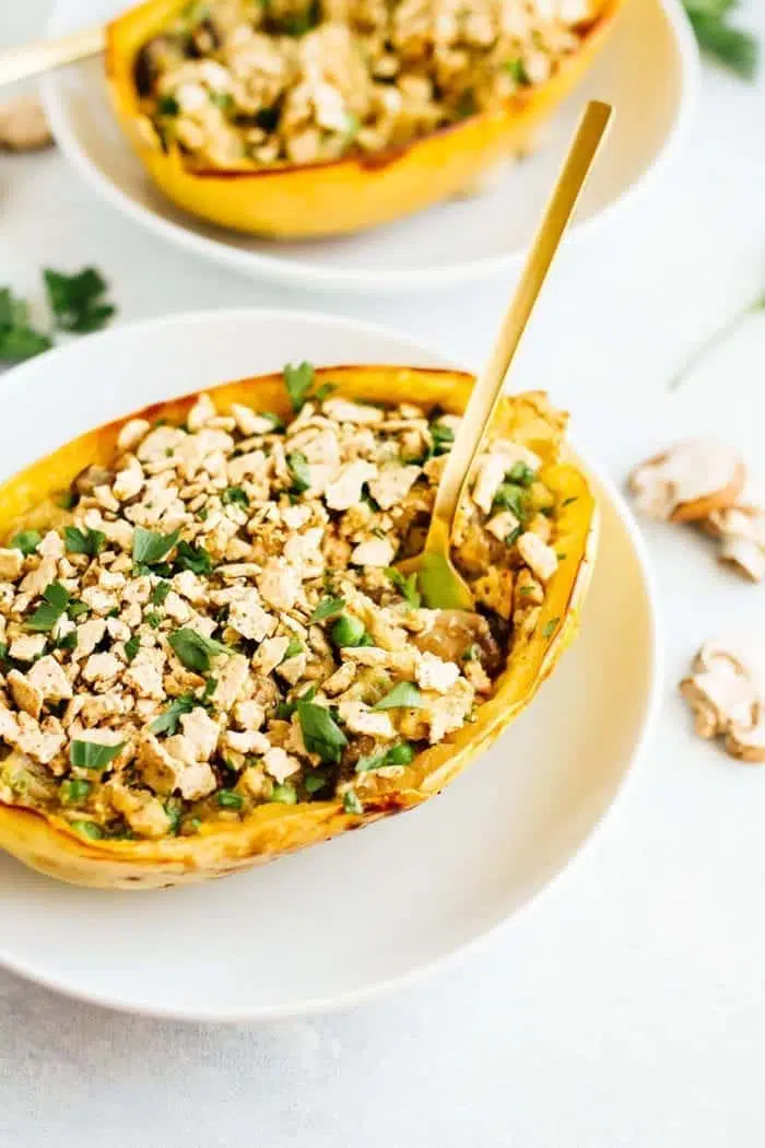 An overhead view of spaghetti squash tuna noodle casserole boats on a white plate.