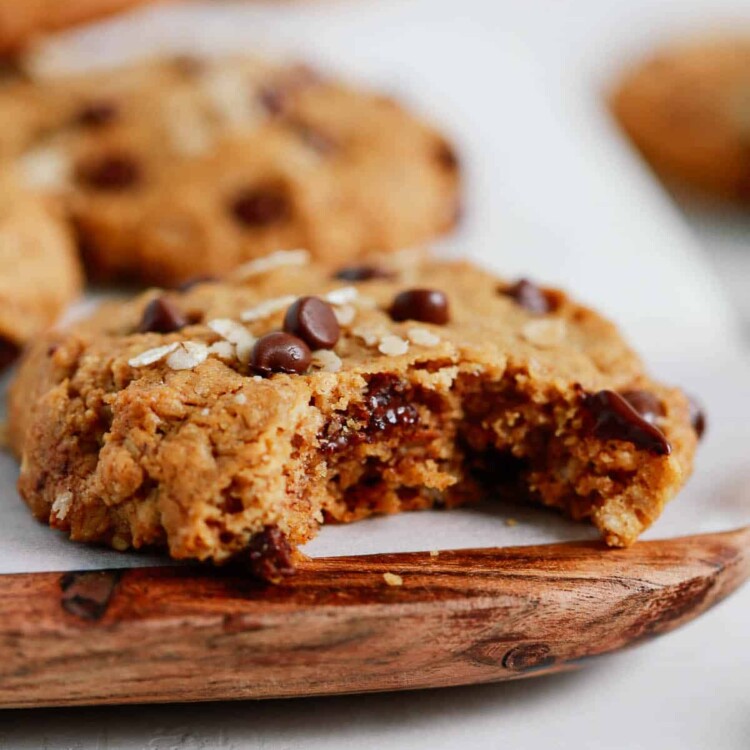 Chocolate chip cookies with a bite taken out of it on a wooden serving board