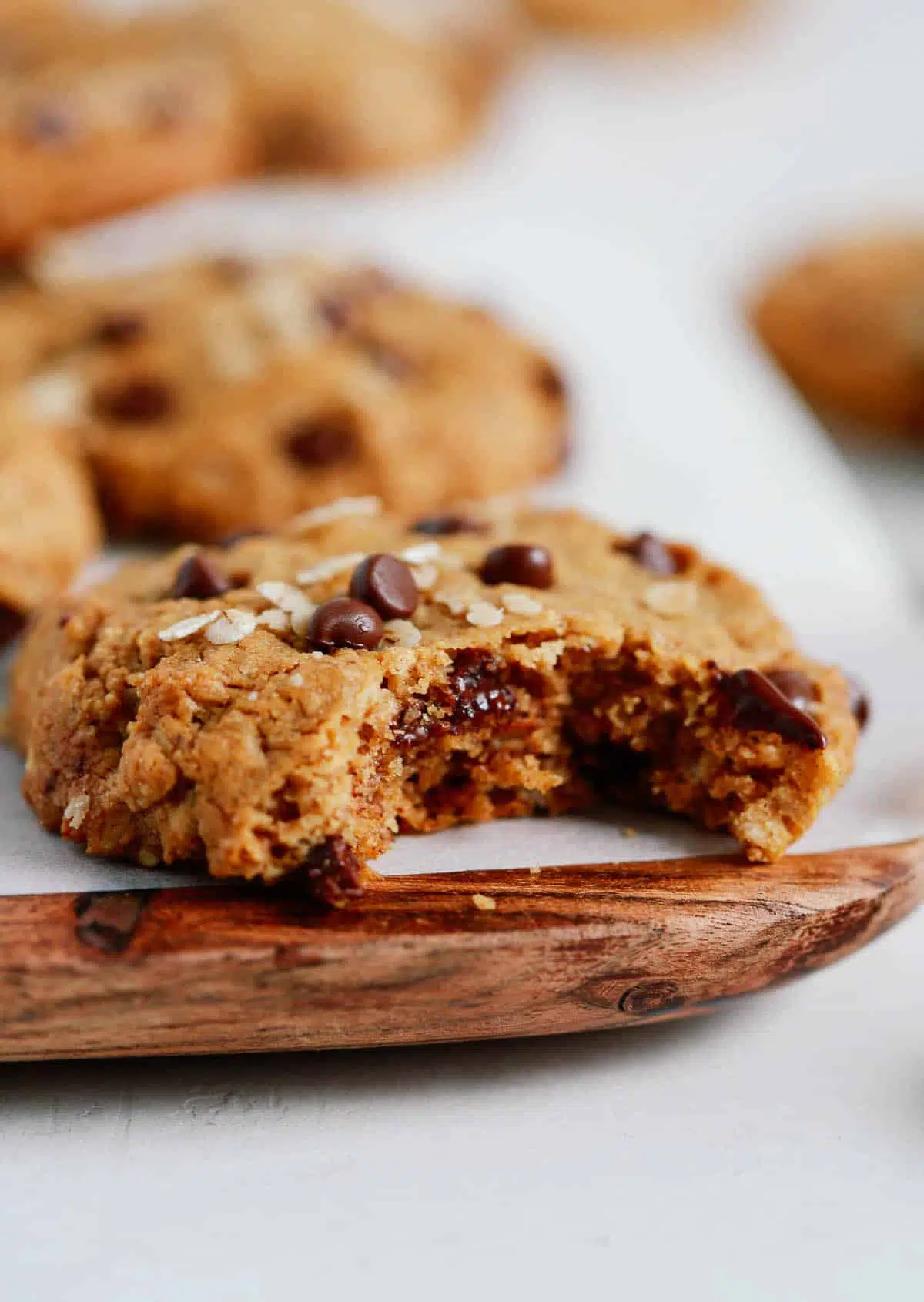 Chocolate chip cookies with a bite taken out of it on a wooden serving board