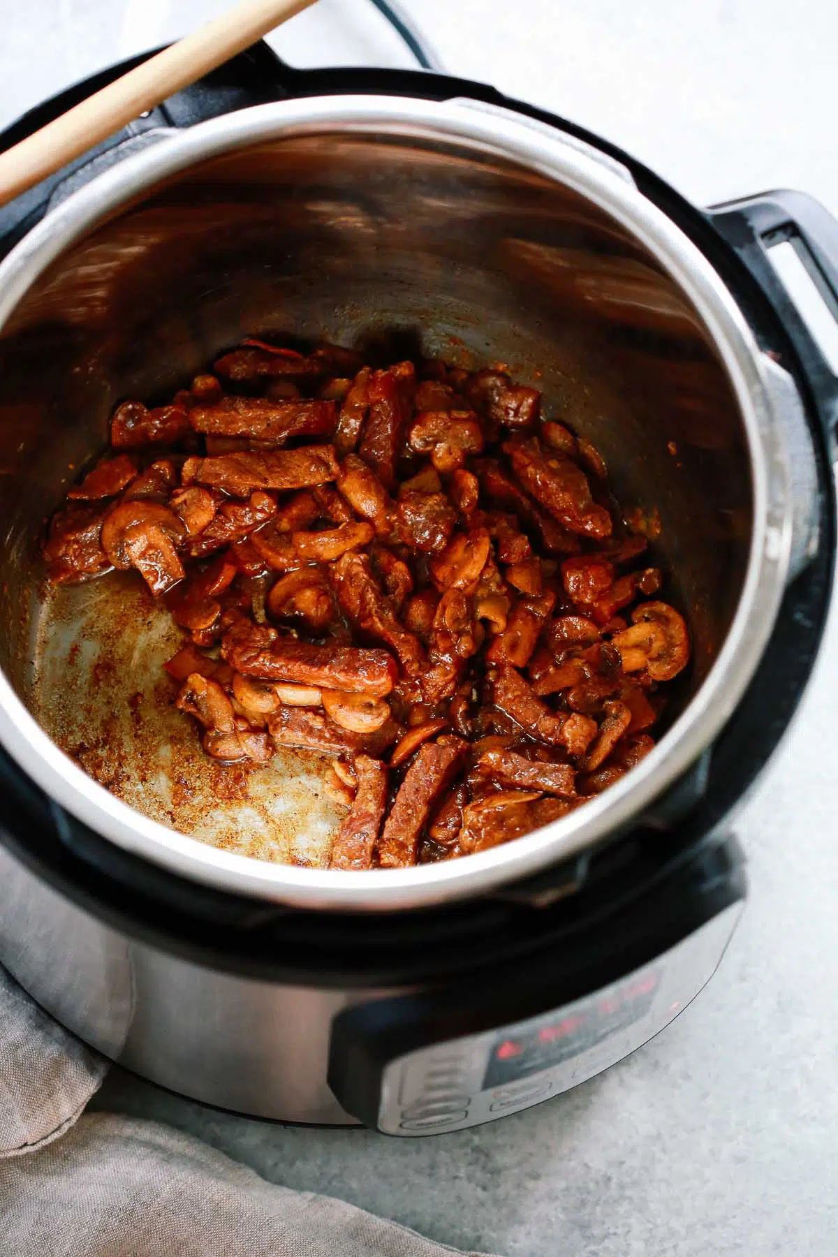 Instant pot with steak and mushroom coated in sauce