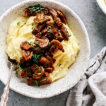 Bowl of mashed potatoes topped with steak and mushrooms
