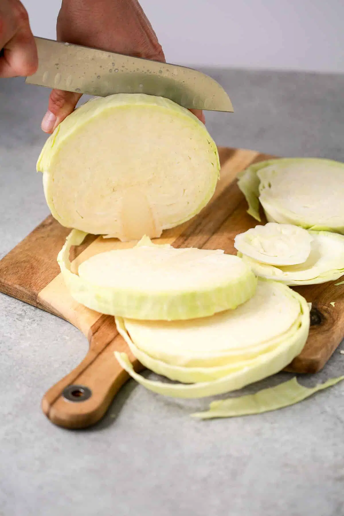 slicing cabbage steaks on a cutting board