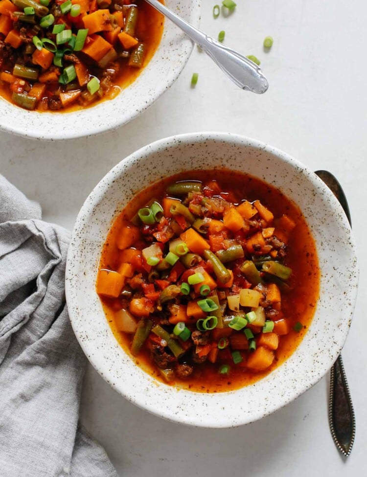 overhead view of a white bowl containing ground beef vegetable soup